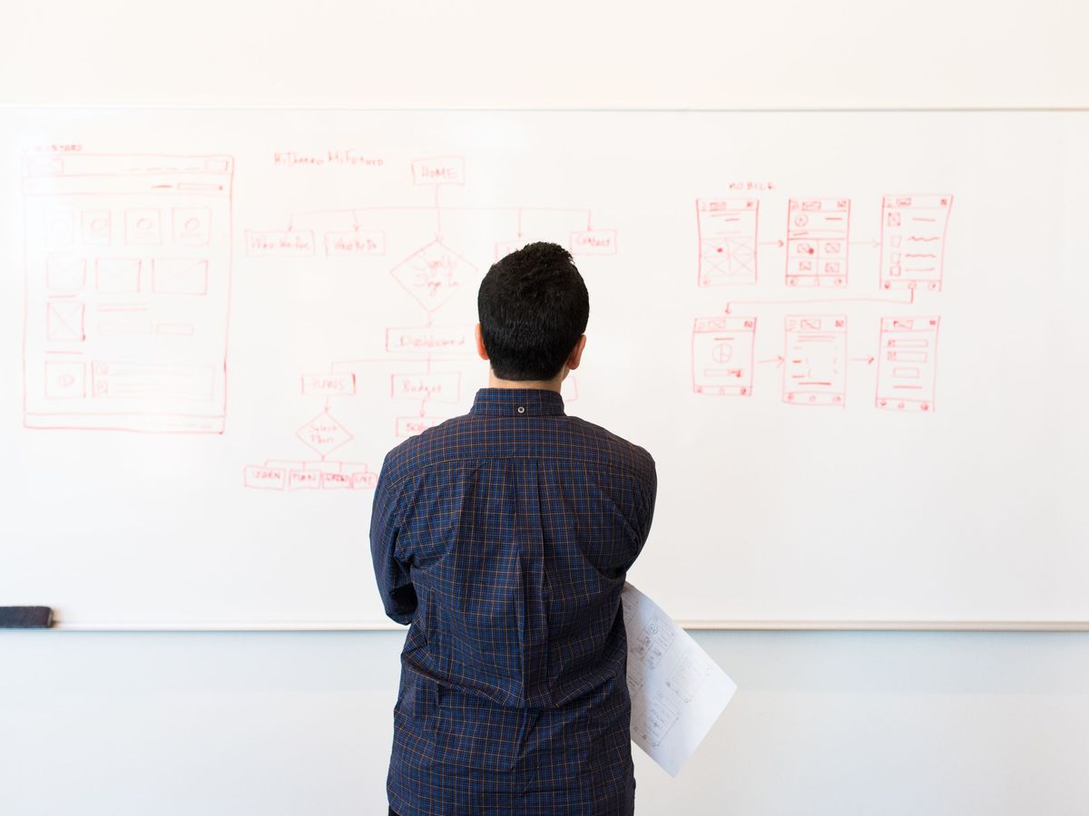 A person studying a process flowchart drawn on a whiteboard