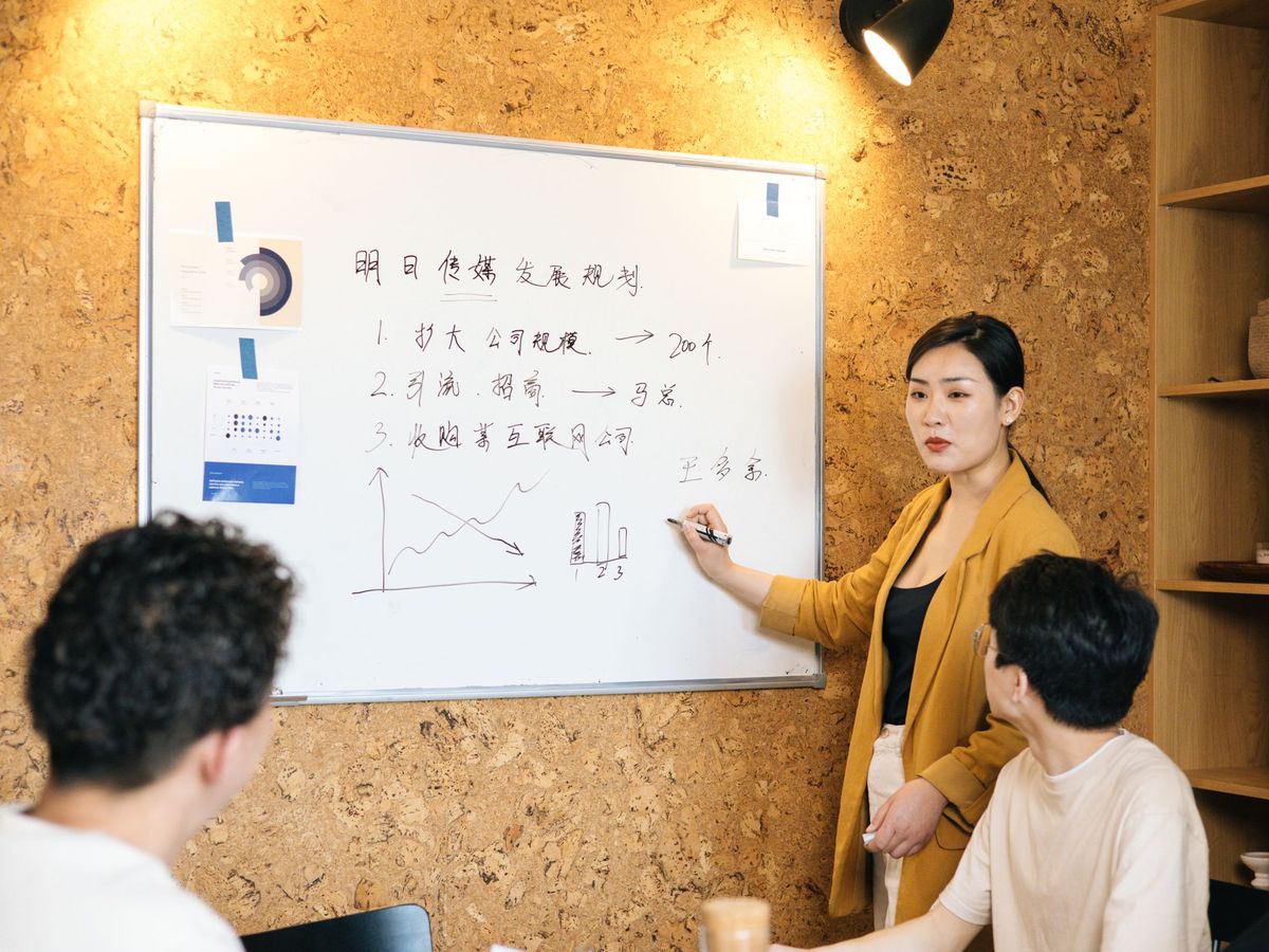 A facilitator writing on a whiteboard while colleagues follow along