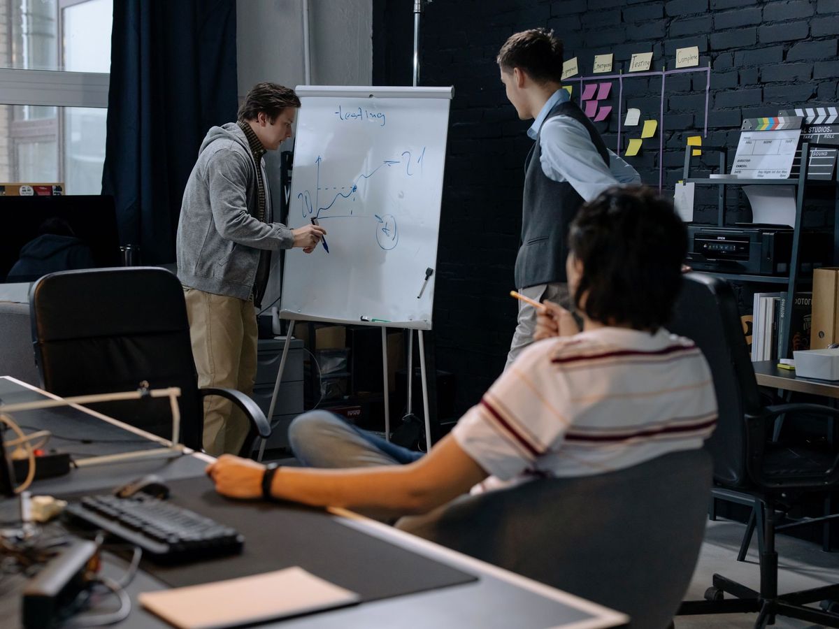 A team in an office working through a plan on a whiteboard